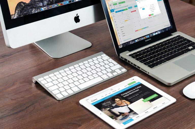 Freelance Website Designer using A sleek office desk setup featuring Apple devices: iMac, MacBook, and iPad.